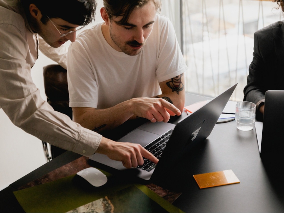Dos chicos señalando y mirando la pantalla de un portatil