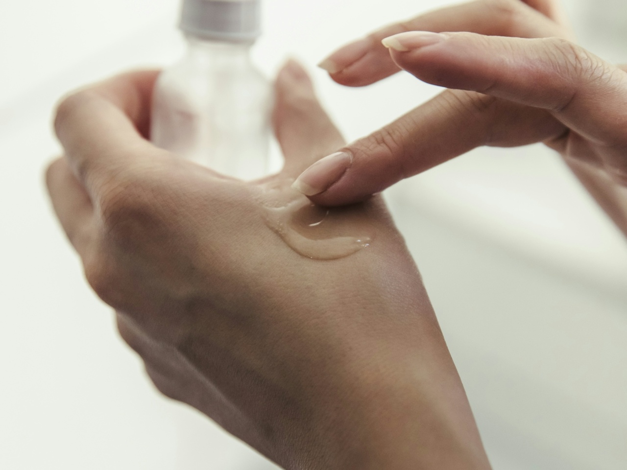 Una chica echandose crema en la mano