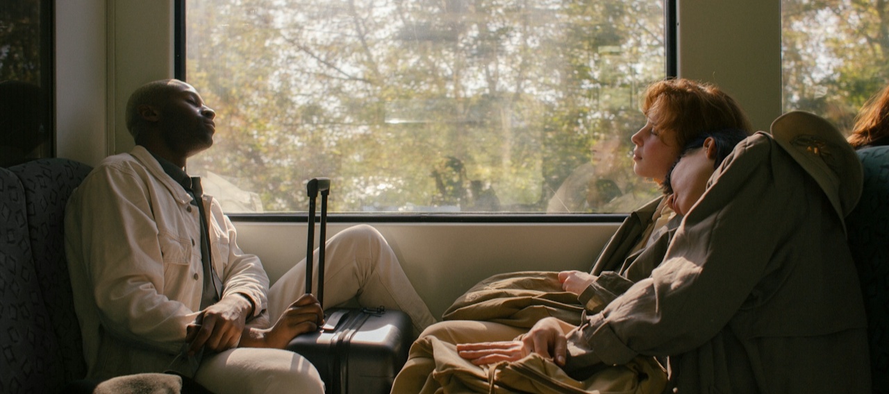 Dos chicos dormidos en un tren con maletas