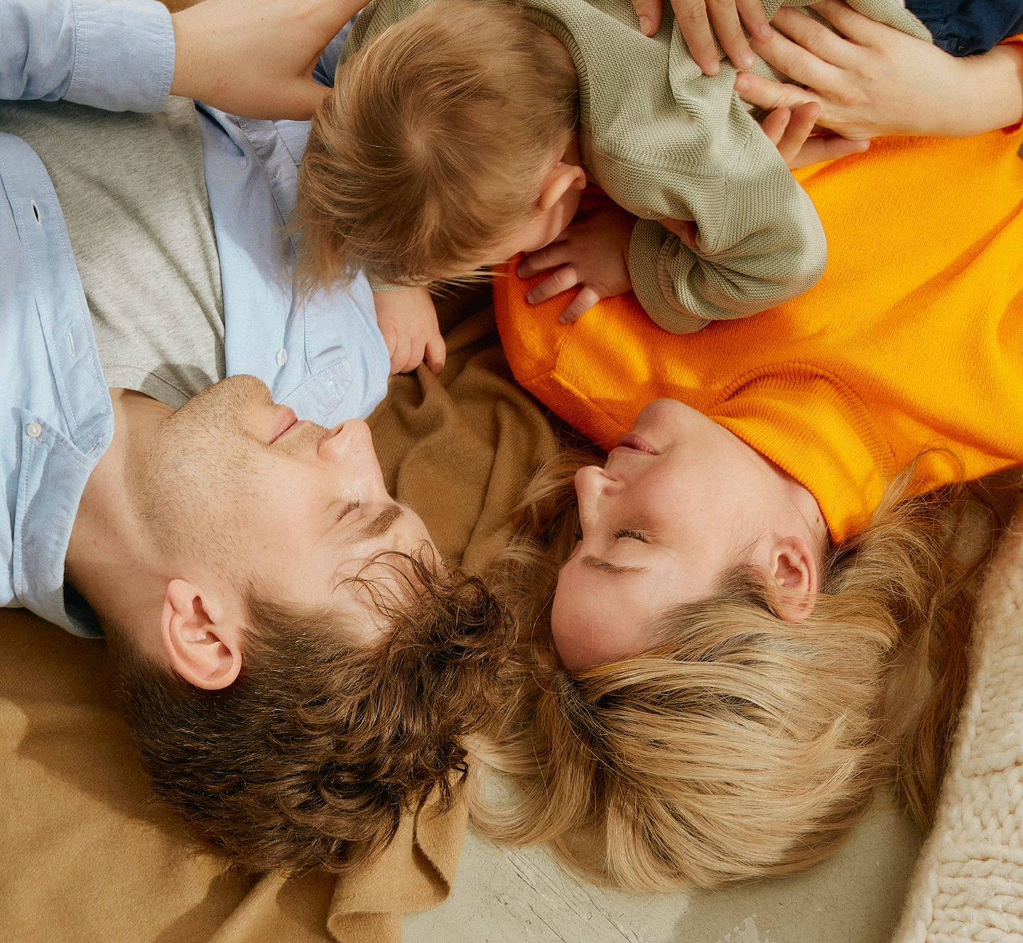 Un chico, una chica en el suelo tumbados y un niño encima