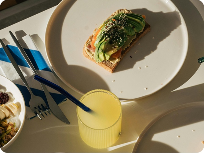 Un plato con un sandwich y una bebida al lado